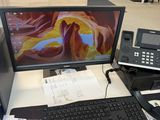 a desk with a computer monitor, keyboard, and phone on it