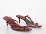 red and brown leather sandals with red straps on a white surface