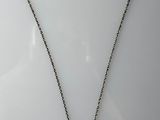 a silver necklace with a cross on a chain on a white surface