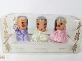 trois petites figurines dans une boîte transparente posée sur une surface blanche