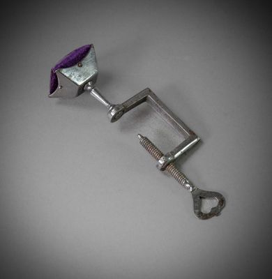 une pince métallique avec une poignée violette posée sur une table