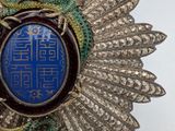 silver broochle with blue stone surrounded by silver leaves