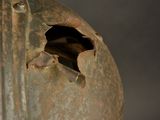 a rusted helmet with a hole in the side
