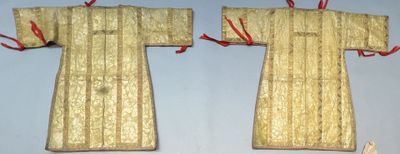 two pieces of gold cloth with red ribbons hang on a wall