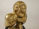 gold owl figurine on black base with white background