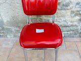 a red chair sitting on a tile floor next to a stone wall