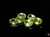 four green peridots on a black surface