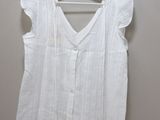 the shirt is white and has ruffles on the shoulders