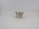 a silver plated bowl with a handle on a white surface