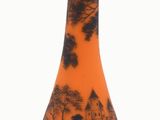un vase noir et orange posé sur une surface blanche