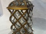 brass and glass candle holder with a bird on top of it