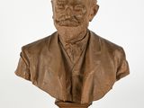 statue représentant le buste d'un homme barbu, posée sur un socle en bois