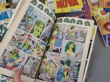 a person holding a comic book open on a table