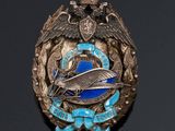 une image représentant un insigne argenté et bleu sur fond noir