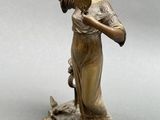 statue of a woman holding a fan and a bird on a rock