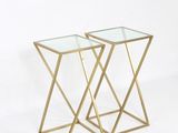 une paire de tables d'appoint dorées avec des plateaux en verre