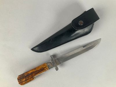 two knives and a knife sheath on a white surface