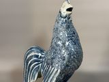 une figurine de coq bleue et blanche posée sur une table