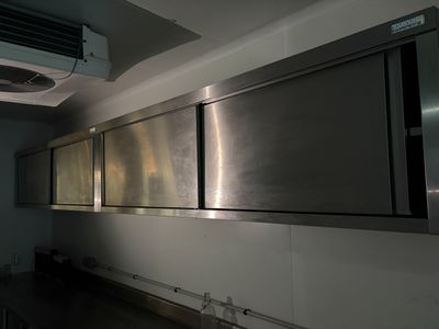 des armoires en acier inoxydable dans une cuisine professionnelle équipée d'un ventilateur au plafond