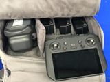 a camera and a video game controller in the back pocket of a bag