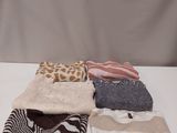 several sweaters and scarves laid out on a white table