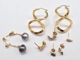 plusieurs paires de boucles d'oreilles et un collier posés sur une surface blanche