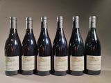 six bottles of wine are lined up in a row on a table