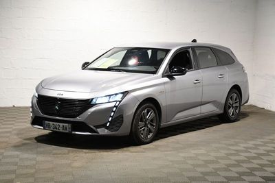 La voiture argentée est garée dans une pièce blanche au sol carrelé en damier.