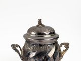 an antique silver teapot with a lid on a white background