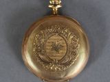 a gold pocket watch with a picture of a man on it