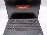 the laptop is open on a white surface with a red lenovo logo on the screen