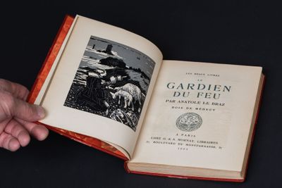 quelqu'un tient un livre ouvert sur lequel figure la photo d'un homme portant un chapeau