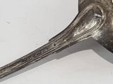 a metal spoon with a bird shaped handle on a white surface