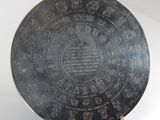 an old silver plate with writing on it sitting on a table