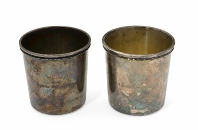 deux vieilles tasses en métal posées l'une à côté de l'autre sur une surface blanche