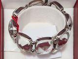 a silver bracelet with red stones on it in a red box