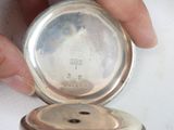 a person holding a silver pocket watch in their hand