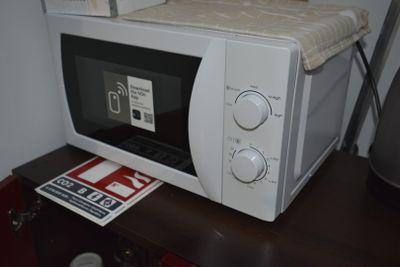 a microwave sitting on top of a table next to a lamp