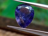 un gros plan d'un saphir bleu tenu par une paire de pinces
