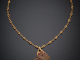 un collier en or avec un pendentif en pierre rouge, monté sur une chaîne en or