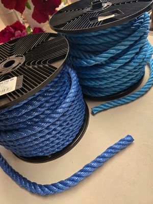 deux bobines de corde bleue posées sur une table, avec des fleurs en arrière-plan