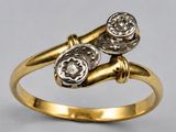 a close up of a gold ring with two diamonds on it