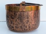 a large copper pot with a handle on a white surface