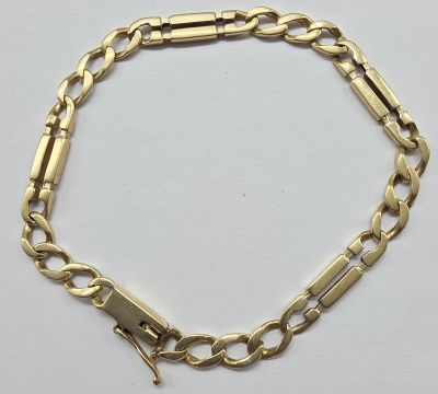 a close up of a gold chain bracelet on a white surface