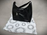 black leather handbag sitting on top of a white and black bag