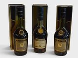 three bottles of liquor sitting next to each other on a white surface