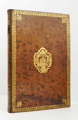 un livre en cuir marron avec des bordures dorées et un emblème doré