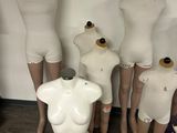 Plusieurs mannequins sont alignés en rang devant un mur blanc
