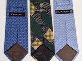 three different colored ties with labels on them on a white surface