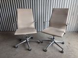 pair of office chairs with wheels in front of a corrugated wall